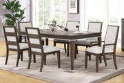 Mesa rectangular marrón con seis sillas con acolchado blanco en marco marrón en una sala neutral con ventanas.