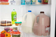 Nevera abierta con botellas de leche y jugo dentro.